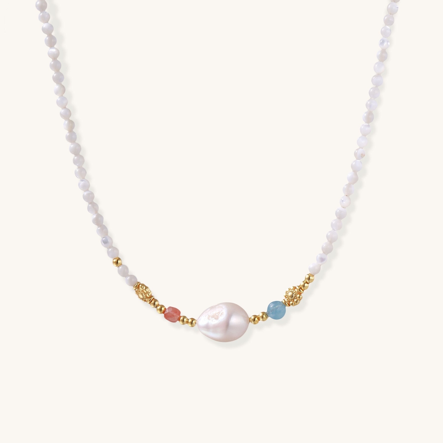 Delicate white beaded necklace with central freshwater pearl and gold-toned emerald accents on white background.