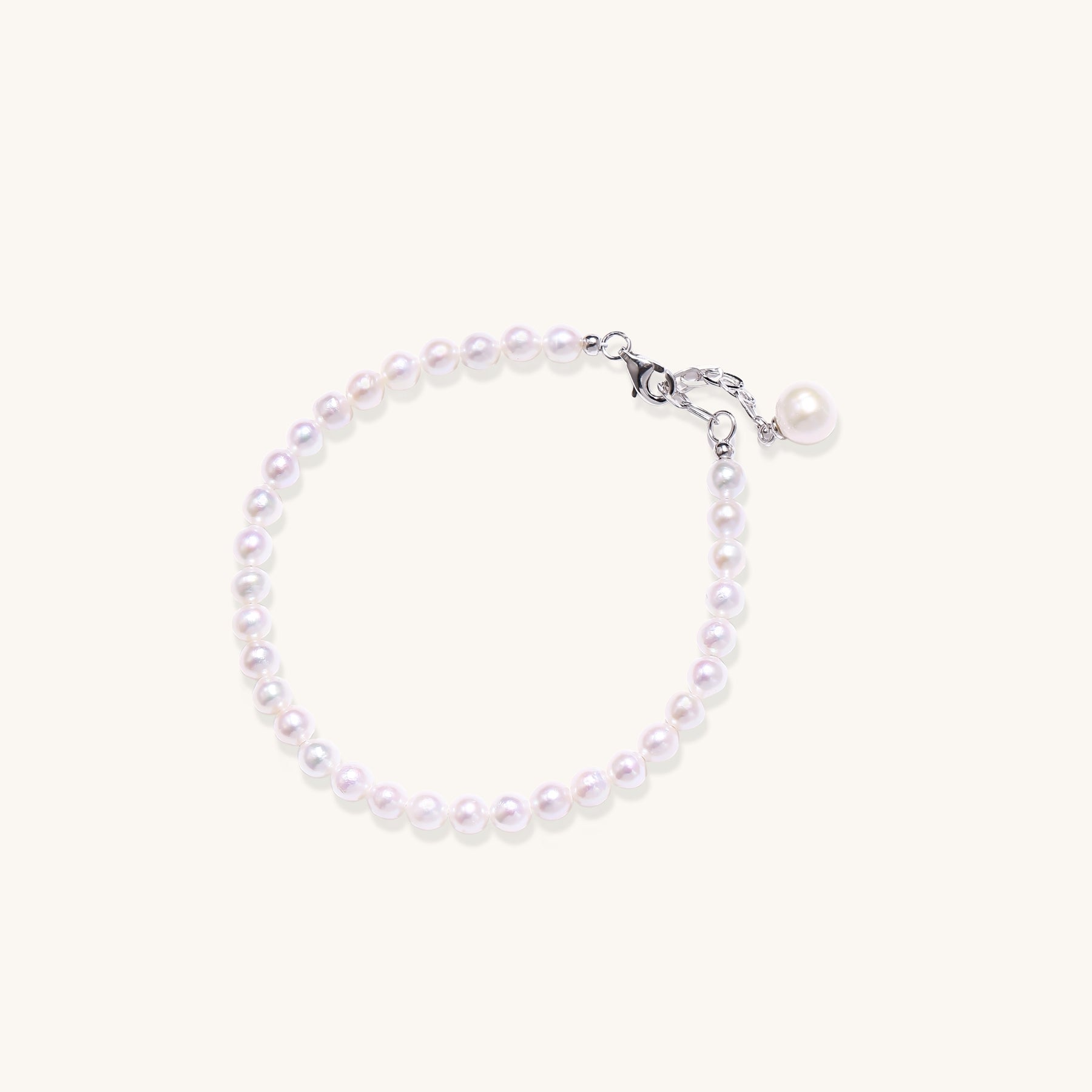 Delicate sterling silver bracelet with small freshwater pearls and adjustable chain on neutral background.