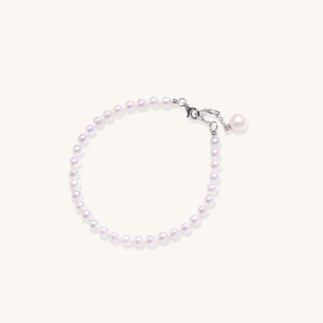 Delicate sterling silver bracelet with small freshwater pearls and adjustable chain on neutral background.