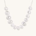 Sterling silver necklace with asymmetrically placed white pearls of varying sizes on neutral background