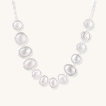 Sterling silver necklace with asymmetrically placed white pearls of varying sizes on neutral background