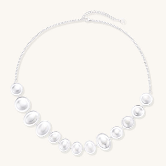 Sterling silver necklace with asymmetrically placed white pearls of varying sizes on neutral background