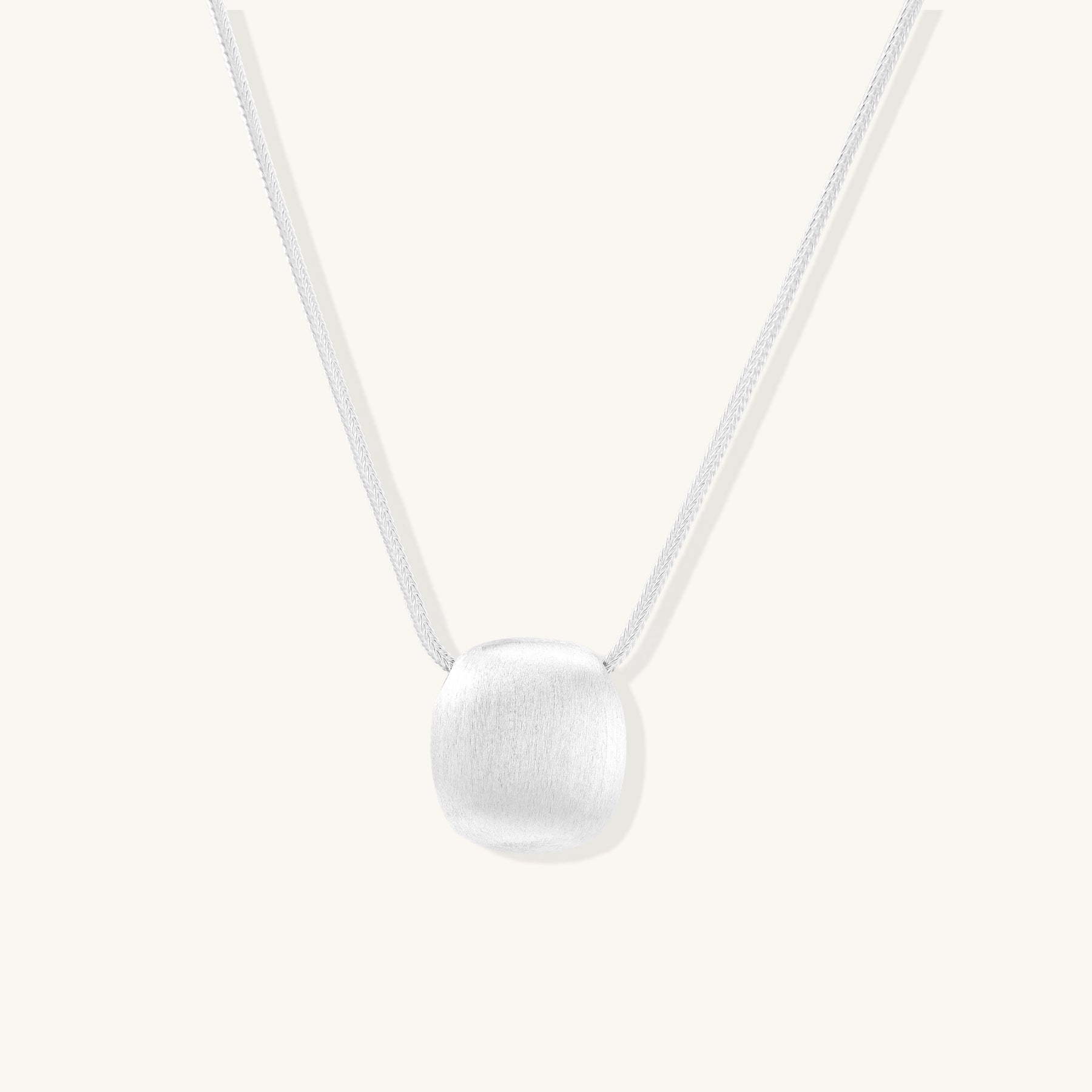 Minimalist sterling silver necklace with brushed square pendant on adjustable chain against white background.