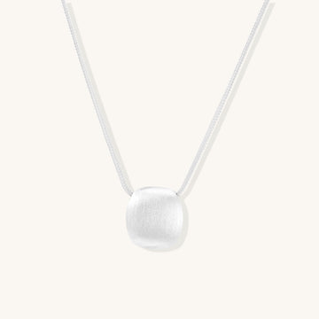 Minimalist sterling silver necklace with brushed square pendant on adjustable chain against white background.
