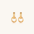 Geometric gold earrings with ribbed linear top section and circular drop elements on white background.