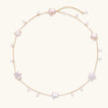 Delicate gold chain necklace with star-shaped baroque pearls and small freshwater pearls on cream background.