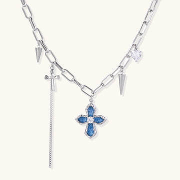 18K gold plated brass chain necklace featuring blue cross pendant with zirconia center stone and spike charms on white background.