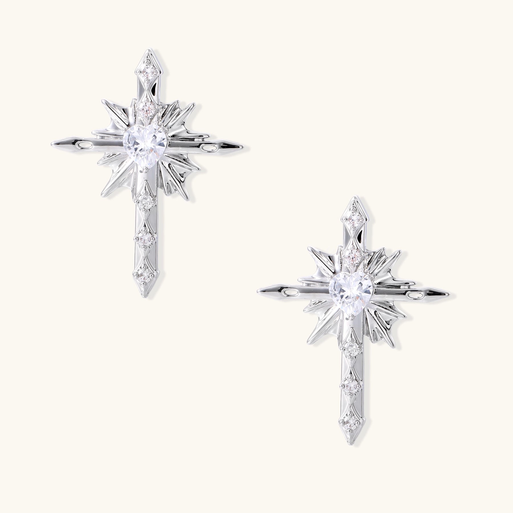 Gold-plated brass starburst cross earrings with central zirconia stones on white background.